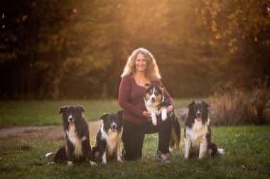 Anja Jakob kniend im Gegenlicht mit ihren Border Collies